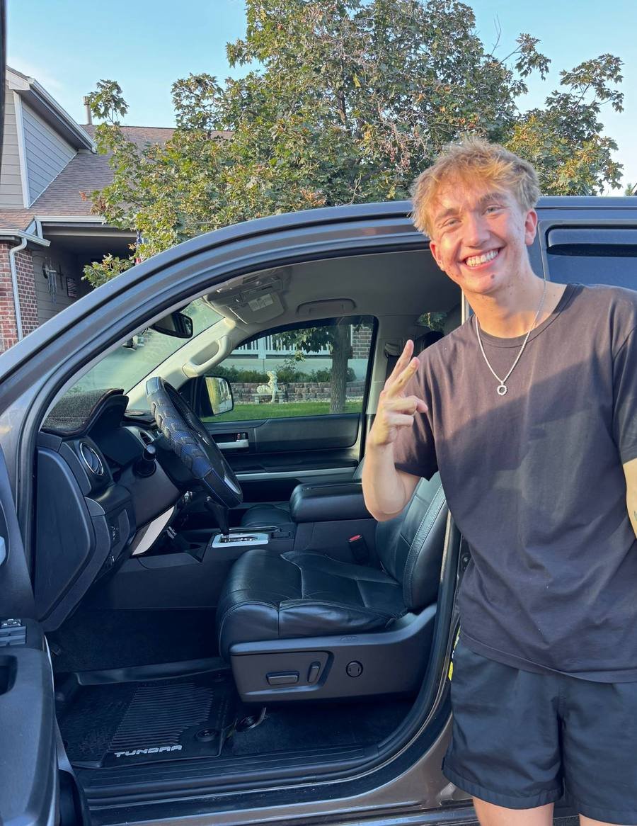 Ben Blondo, owner of Blondo’s Mobile Detailing, smiling and giving a peace sign beside a freshly detailed Toyota Tundra with its door open